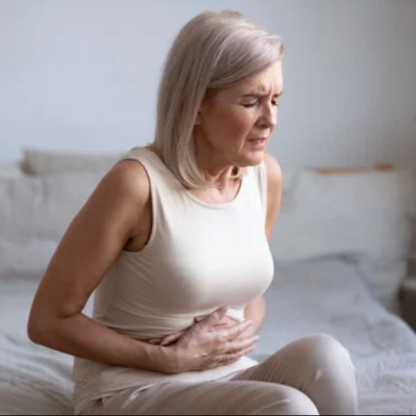 Woman experiencing stomach pain in a bedroom setting