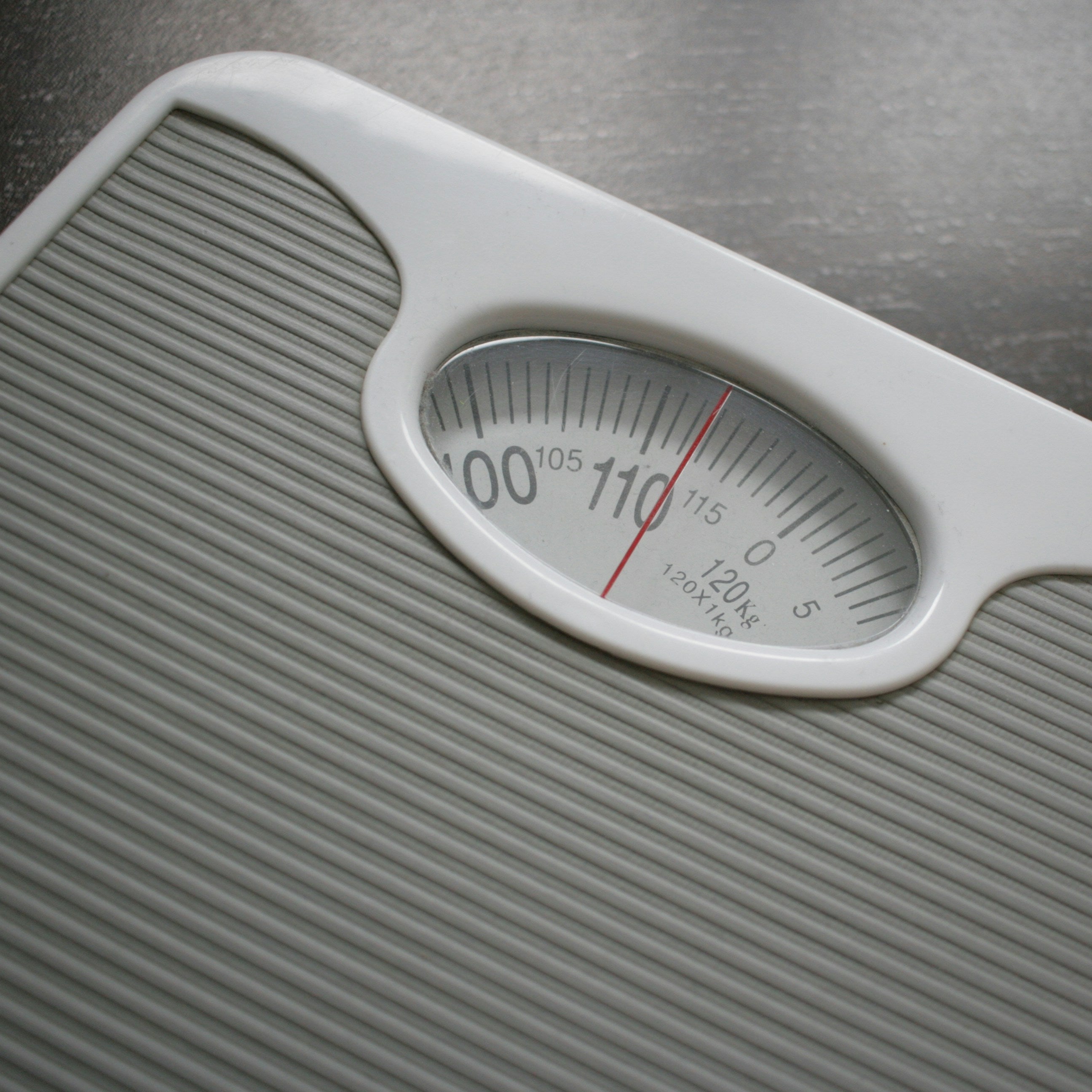 White bathroom scale on a dark surface
