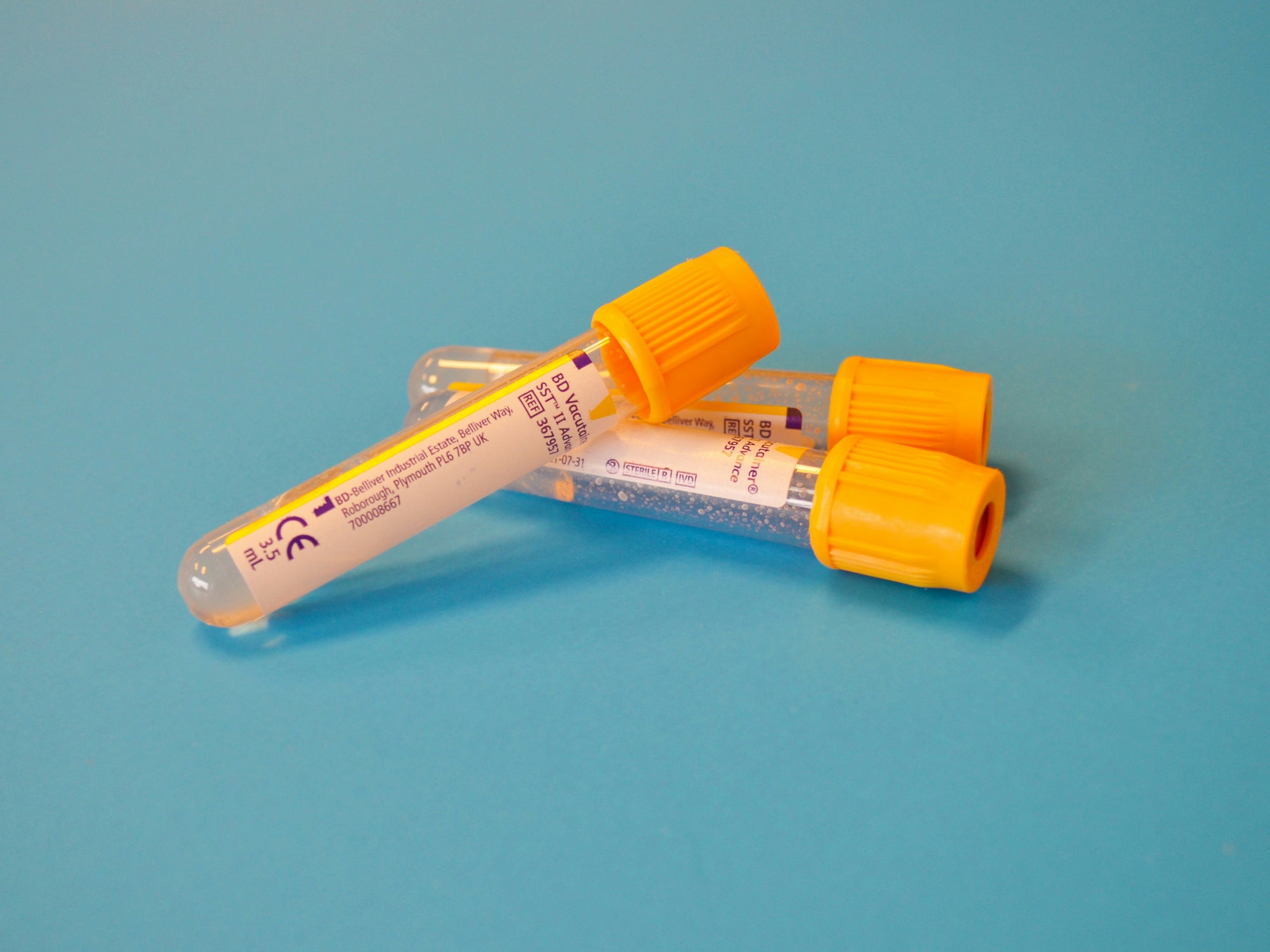 Two test tubes with orange caps on a blue background