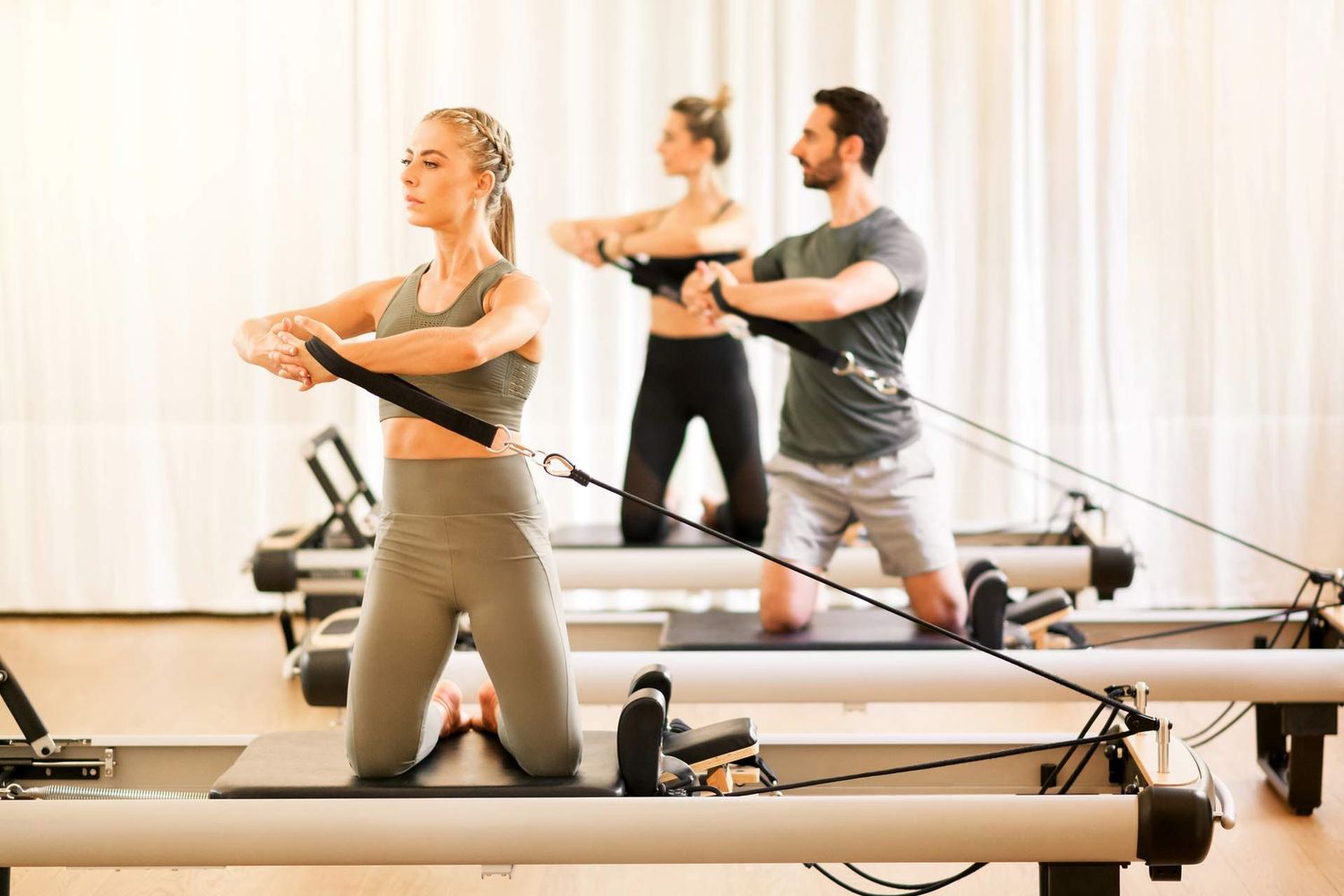 Group of people exercising on Pilates reformers in a studio.