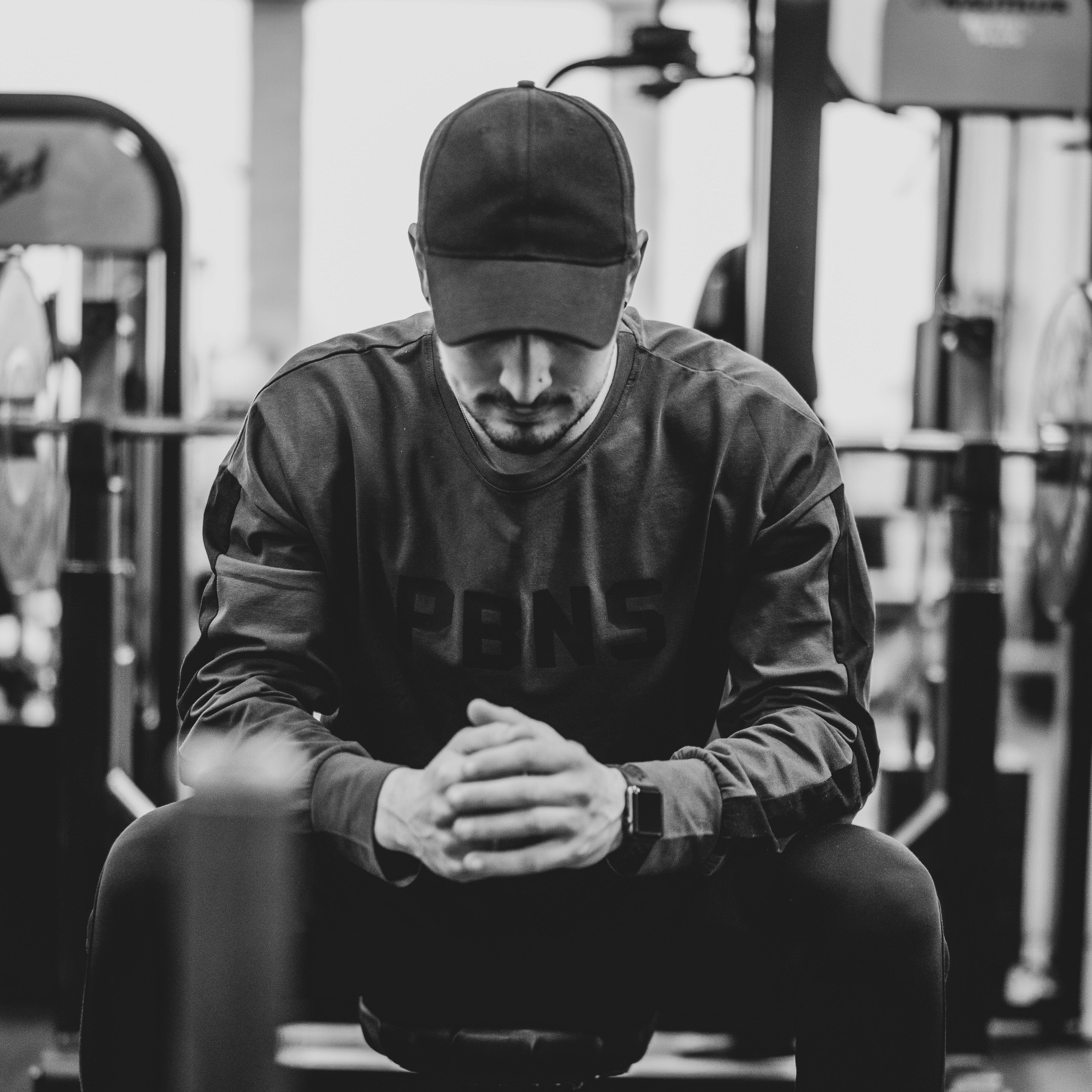 Black and White image of a man resting in between sets while weightlifting.
